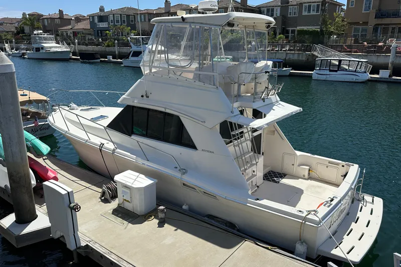 Slide: The Image of Riviera 3600 Sport Yacht 1999 docked at marina, surrounded by waterfront homes. - 24