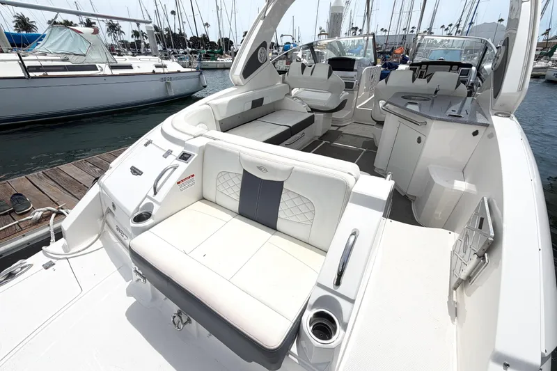 Slide: The Image of 2014 Chaparral 327 SSX boat interior with luxurious seating and sleek design at a marina. - 13