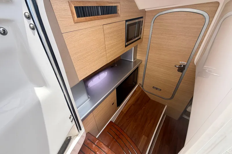 Slide: The Image of 2014 Chaparral 327 SSX cabin interior with wood finish, kitchenette, and compact design. - 27
