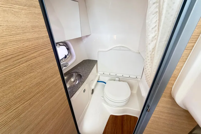 Slide: The Image of 2014 Chaparral 327 SSX boat bathroom with sink, toilet, and wood accents. - 28
