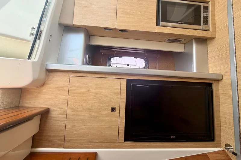 Slide: The Image of 2014 Chaparral 327 SSX interior with microwave and TV, featuring wood paneling. - 33