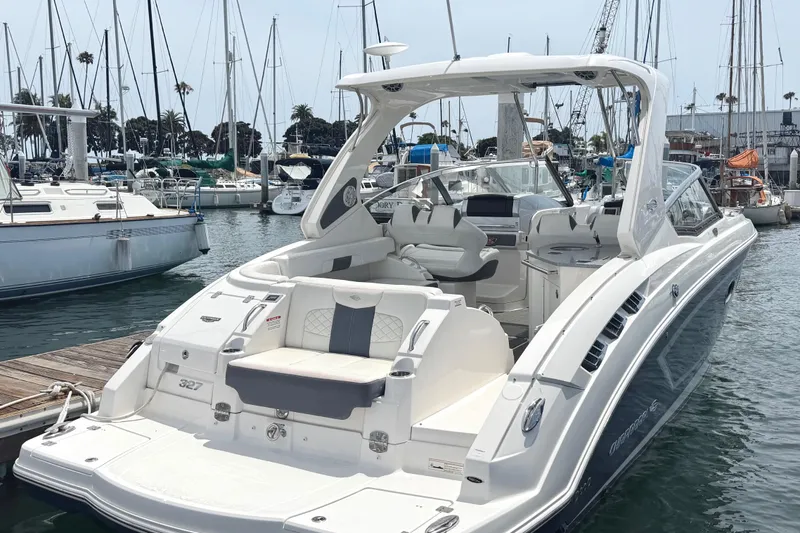 Slide: The Image of 2014 Chaparral 327 SSX boat docked in a marina, showcasing sleek design and spacious seating. - 4