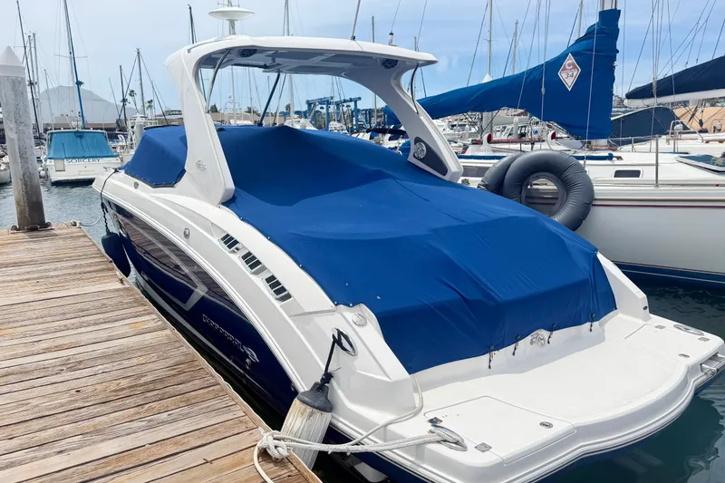 Slide: The Image of 2014 Chaparral 327 SSX boat docked, covered with a blue tarp, in a marina setting. - 6