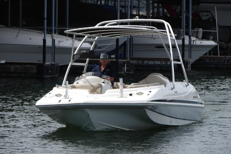 Slide: The Image of 2017 Hurricane SunDeck Sport 202 IO boat cruising on water with a person at the helm. - 9