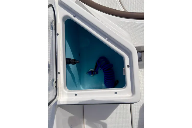 Slide: The Image of 2025 Yamaha Boats 222 FSH Sport storage compartment with coiled hose. - 31