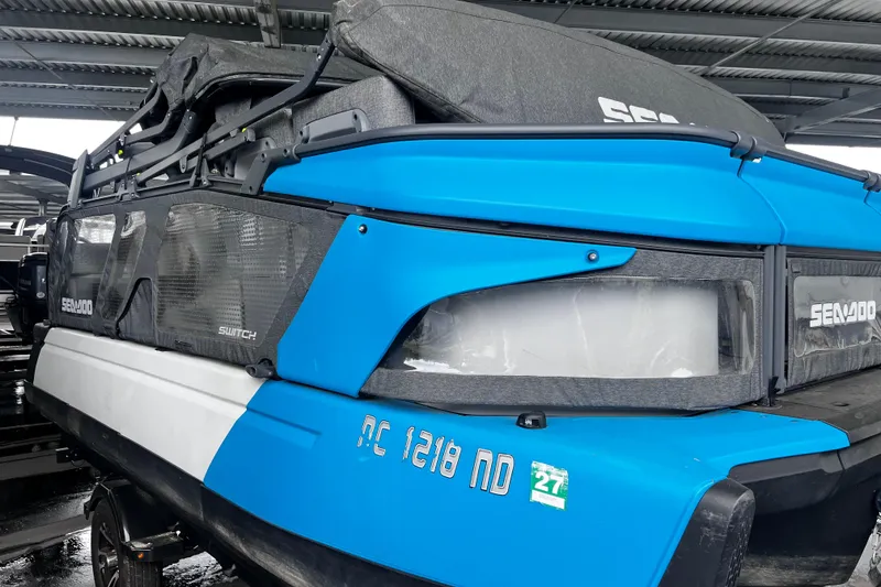 Slide: The Image of 2023 Sea-Doo Switch Cruise 18 pontoon boat in blue under a metal roof. - 8