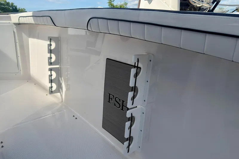 Slide: The Image of 2026 Yamaha Boats 255 FSH Sport H interior detail with rod holders and cushioned seating. - 11