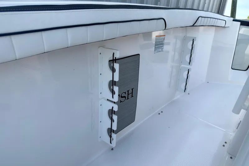 Slide: The Image of 2026 Yamaha Boats 255 FSH Sport H interior detail, featuring sleek white seating and storage compartments. - 12