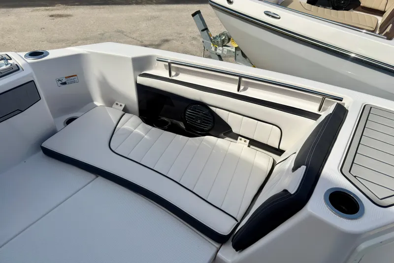 Slide: The Image of 2026 Yamaha Boats 255 FSH Sport H interior seating with sleek white upholstery and cup holder. - 16