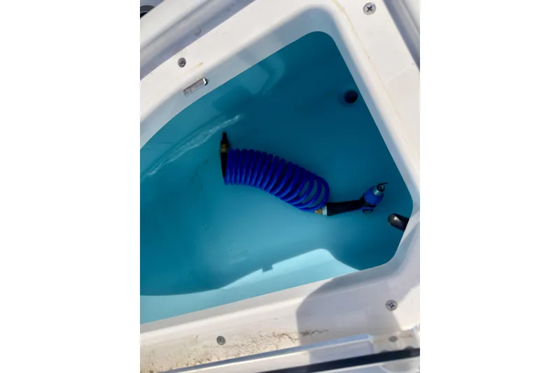 Slide: The Image of 2026 Yamaha Boats 255 FSH Sport H storage compartment with blue hose. - 24