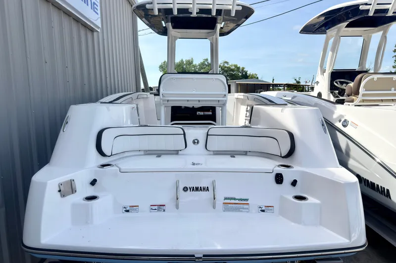 Slide: The Image of 2026 Yamaha Boats 255 FSH Sport H, rear view, white exterior, docked beside another boat. - 25