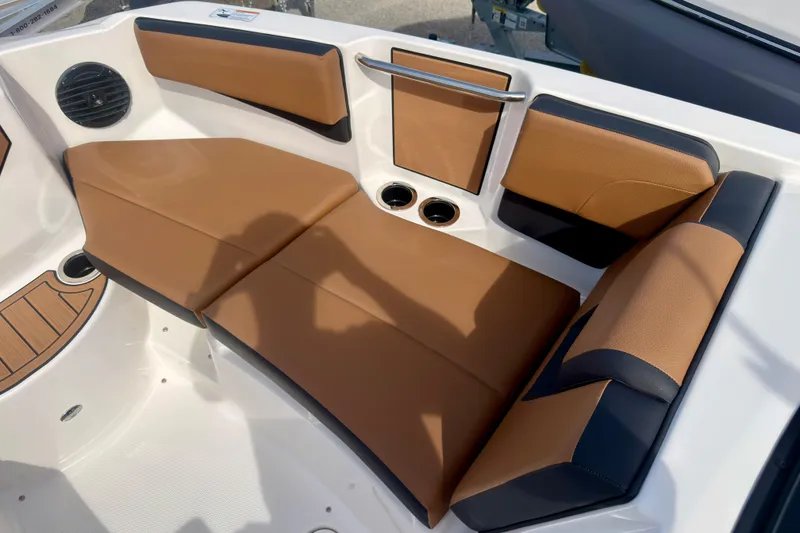 Slide: The Image of 2026 Yamaha Boats 222SD interior seating with tan and black upholstery, cup holders, and speaker. - 24