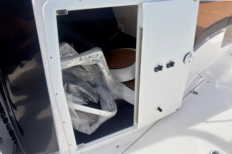 Slide: The Image of Open storage compartment on 2026 Yamaha Boats 222SD, revealing interior space and wrapped items. - 35