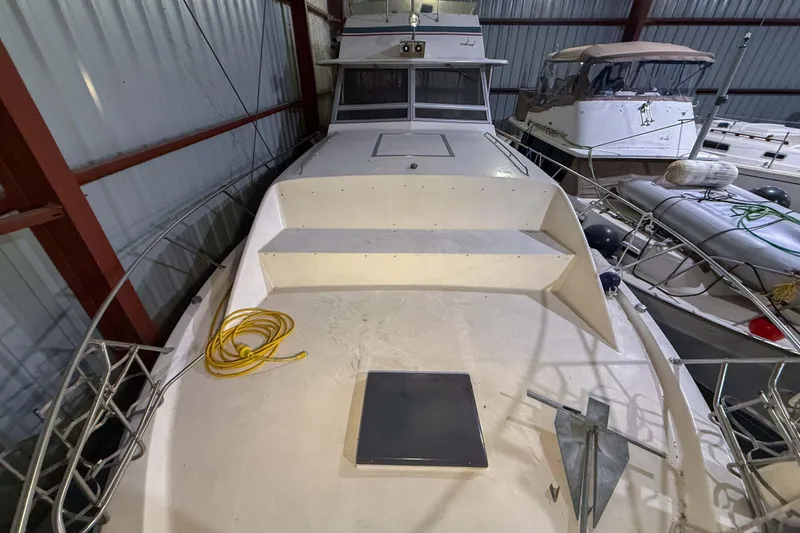 Slide: The Image of 1977 Pacemaker FB Motor Yacht in storage, featuring a spacious deck and moored alongside other boats. - 17