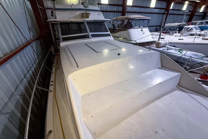 Slide: The Image of 1977 Pacemaker FB Motor Yacht in storage, showcasing its sleek white deck and cabin. - 18
