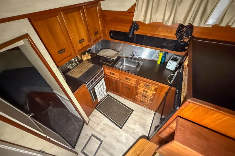 Slide: The Image of 1977 Pacemaker FB Motor Yacht kitchen with wooden cabinets, stove, and sink. - 28