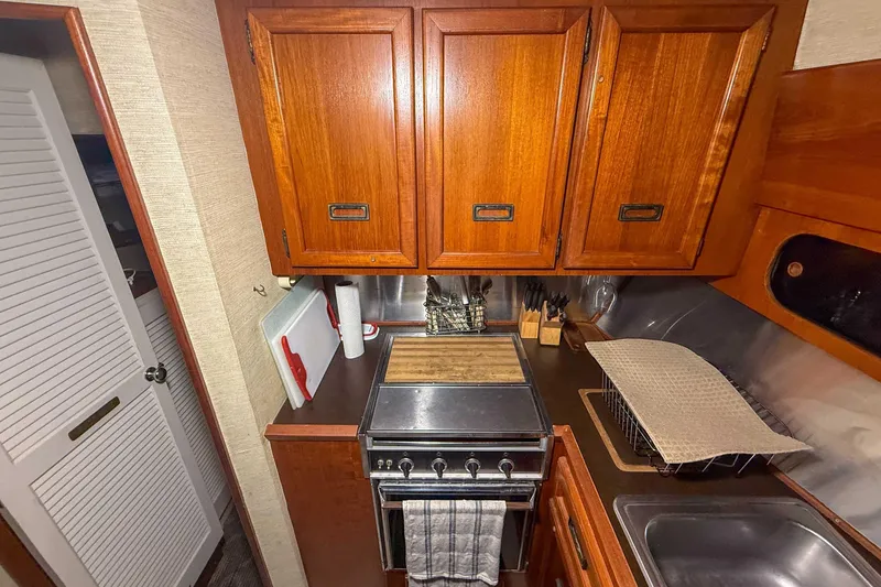 Slide: The Image of 1977 Pacemaker FB Motor Yacht kitchen with wooden cabinets, stove, and sink. - 29