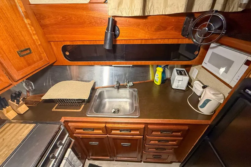 Slide: The Image of 1977 Pacemaker FB Motor Yacht kitchen with wooden cabinets, sink, and appliances. - 30