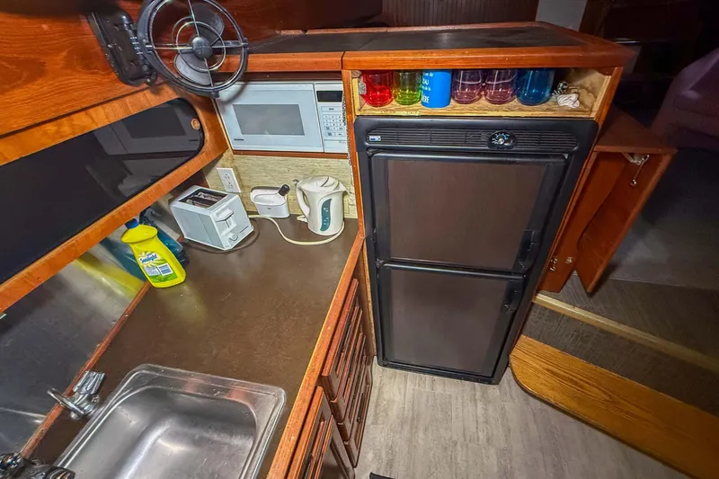 Slide: The Image of 1977 Pacemaker FB Motor Yacht kitchen with sink, microwave, fridge, and countertop appliances. - 31