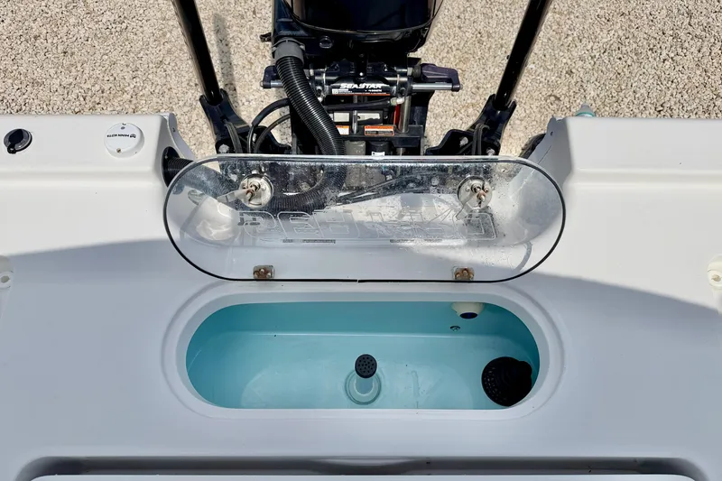 Slide: The Image of 2022 Sea Pro 248 Bay boat livewell with open lid and visible motor components. - 28