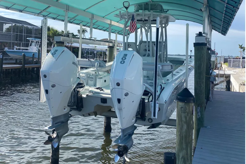 Slide: The Image of 2020 Costa Custom Boats 264 HC with twin Mercury outboards docked under a canopy. - 15