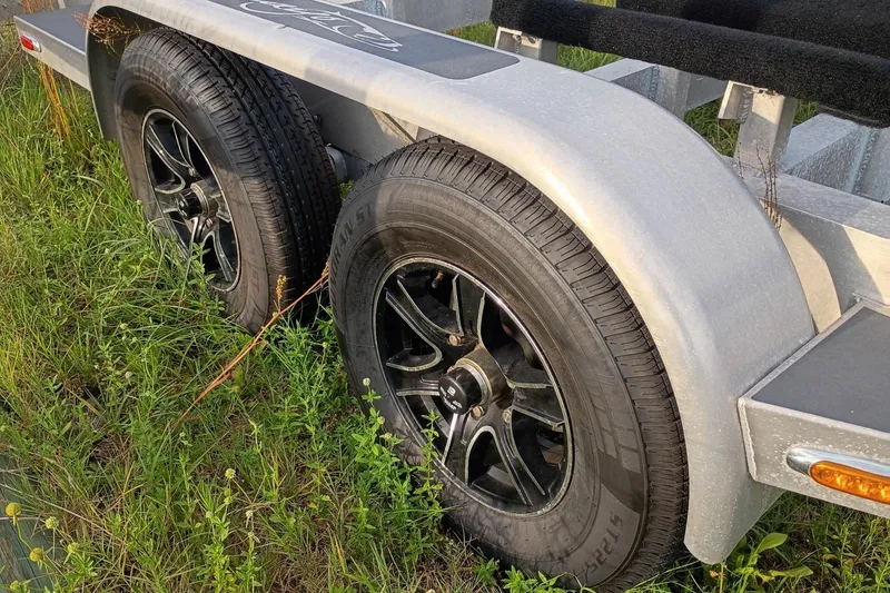 Slide: The Image of Trailer wheels of a 2020 Costa Custom Boats 264HC on grassy terrain. - 29