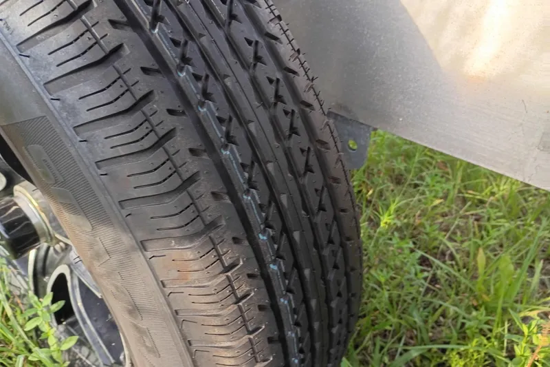 Slide: The Image of Close-up of a tire on a 2020 Costa Custom Boats 264HC trailer. - 30