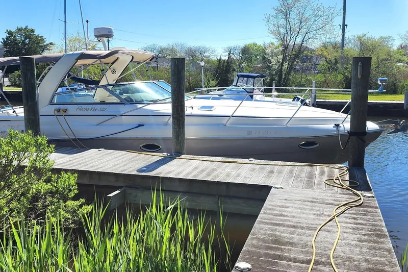 Slide: The Image of 2005 Rinker Fiesta Vee 320 docked at a marina, surrounded by greenery and calm water. - 14