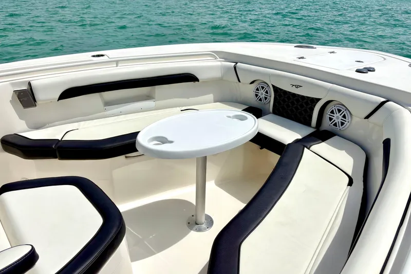 Slide: The Image of 2021 Tidewater 256 CC Adventure boat interior with seating and table on calm water. - 13