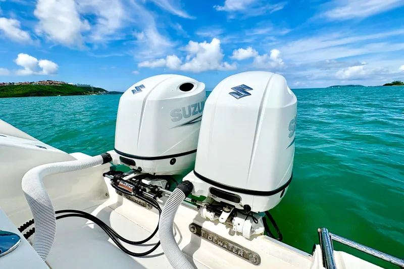Slide: The Image of Twin Suzuki outboard engines on a 2021 Tidewater 256 CC Adventure boat, cruising in clear blue waters. - 19