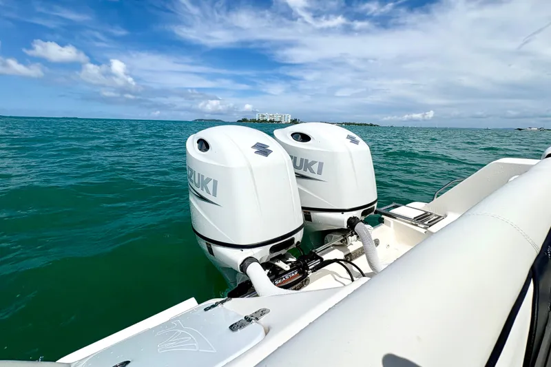 Slide: The Image of 2021 Tidewater 256 CC Adventure boat with dual Suzuki outboard motors on open water. - 20