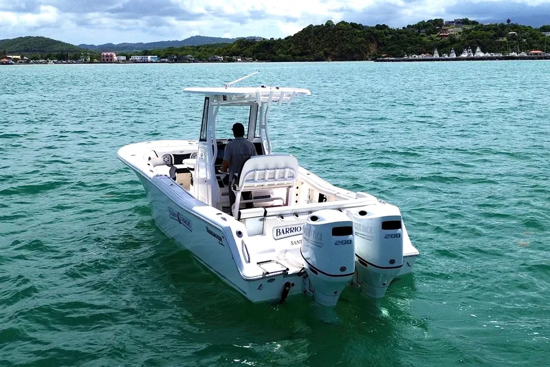 Slide: The Image of 2021 Tidewater 256 CC Adventure boat cruising on turquoise waters near a scenic coastline. - 4