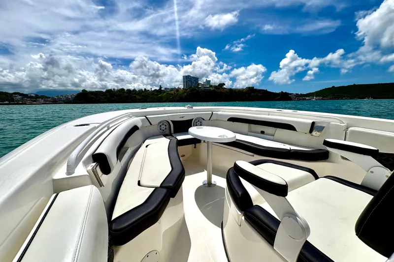 Slide: The Image of 2021 Tidewater 256 CC Adventure boat interior with seating, table, and scenic ocean view. - 8