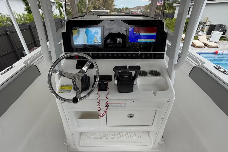 Slide: The Image of 2016 Sea Hunt Gamefish 25 helm with navigation screens and steering wheel. - 14