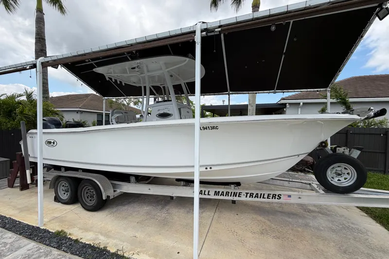 Slide: The Image of 2016 Sea Hunt Gamefish 25 boat on trailer under canopy, parked in residential driveway. - 2