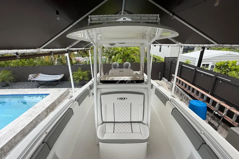 Slide: The Image of 2016 Sea Hunt Gamefish 25 boat interior, featuring seating and helm, near a poolside setting. - 29