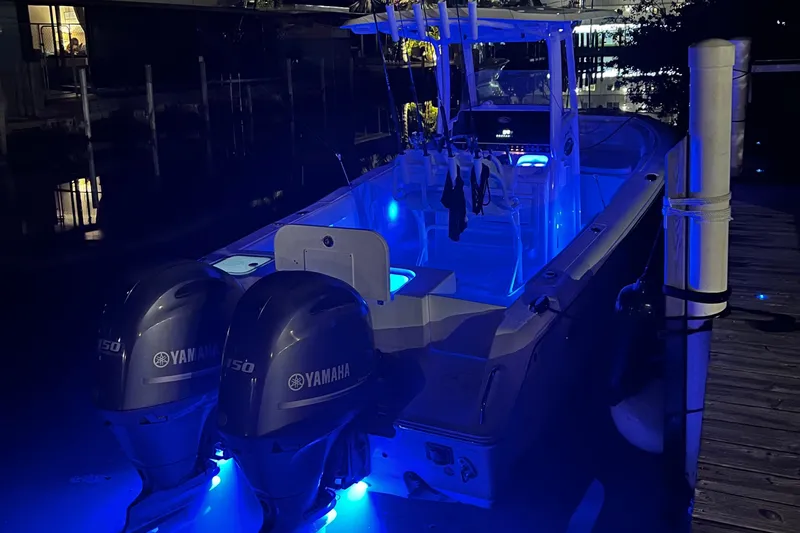 Slide: The Image of 2016 Sea Hunt Gamefish 25 boat with Yamaha engines, illuminated by blue LED lights at night. - 38