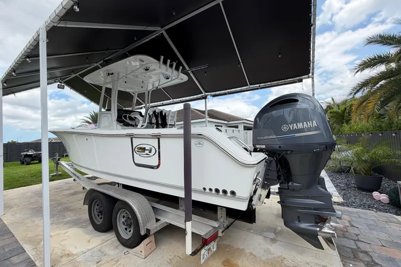 Slide: The Image of 2016 Sea Hunt Gamefish 25 boat on trailer under canopy, featuring Yamaha outboard motor. - 4