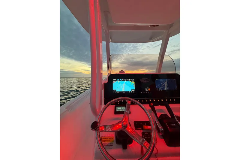 Slide: The Image of 2016 Sea Hunt Gamefish 25 dashboard at sunset, featuring navigation screens and steering wheel. - 40