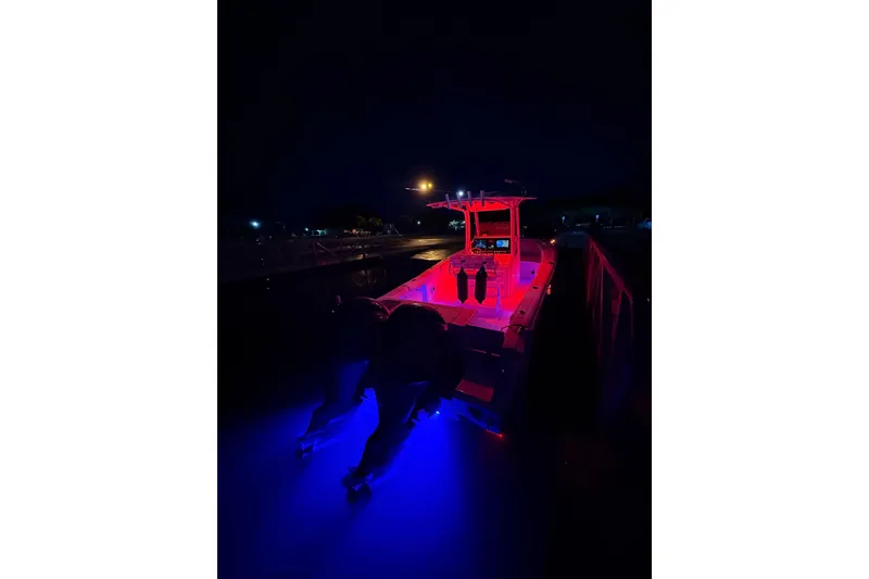Slide: The Image of 2016 Sea Hunt Gamefish 25 boat illuminated with red and blue lights at night. - 41