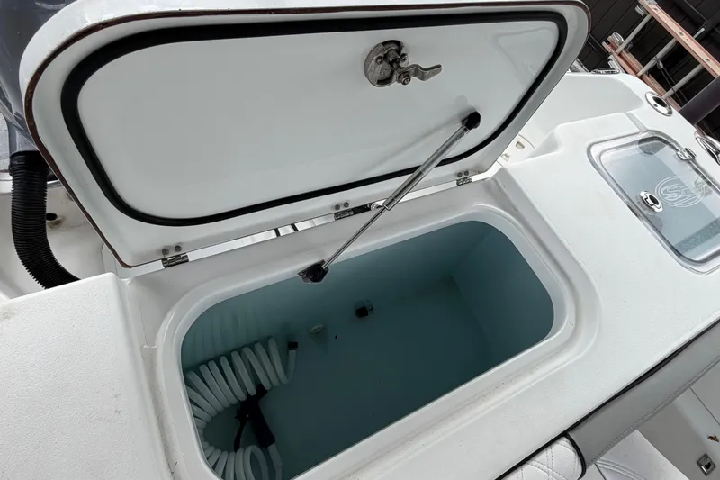 Slide: The Image of Open storage compartment on a 2016 Sea Hunt Gamefish 25 boat, featuring a coiled hose. - 42