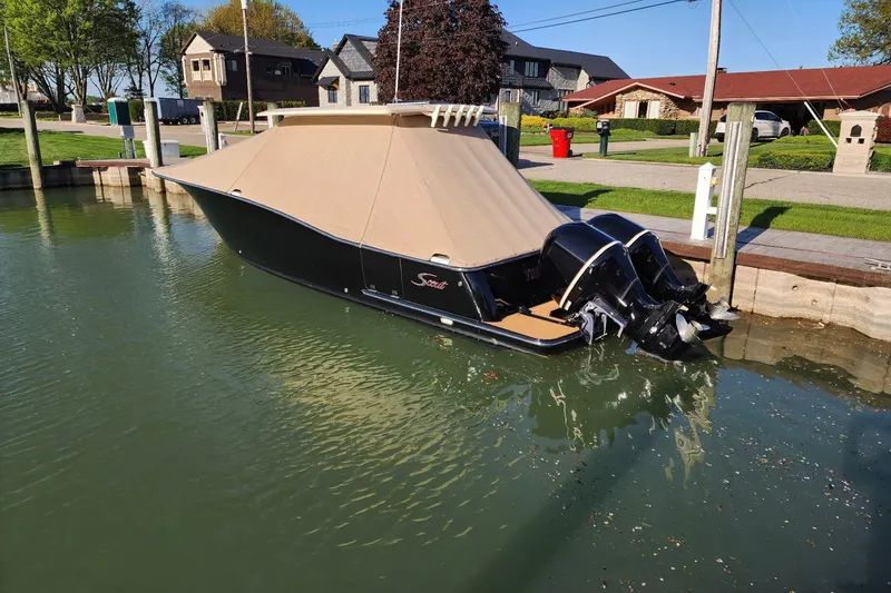 Slide: The Image of 2017 Scout 320 LXF boat docked with cover, twin engines visible. - 1
