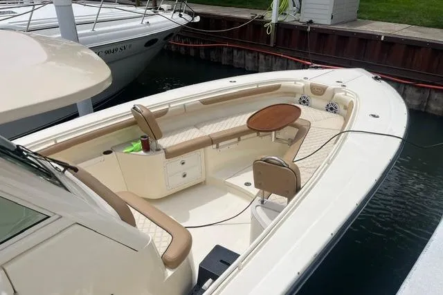 Slide: The Image of 2017 Scout 320 LXF boat with beige seating and wooden table, docked in a marina. - 17