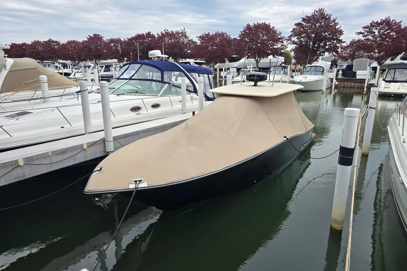 Slide: The Image of 2017 Scout 320 LXF boat covered and docked at a marina with surrounding boats. - 2