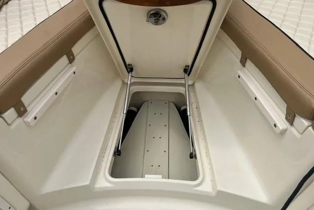 Slide: The Image of 2017 Scout 320 LXF boat storage compartment with open hatch and cushioned seating. - 20