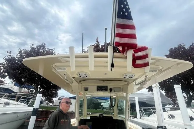 Slide: The Image of 2017 Scout 320 LXF boat with American flag, docked under cloudy sky. - 55