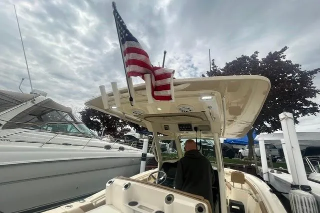 Slide: The Image of 2017 Scout 320 LXF boat with American flag, docked under cloudy sky. - 56