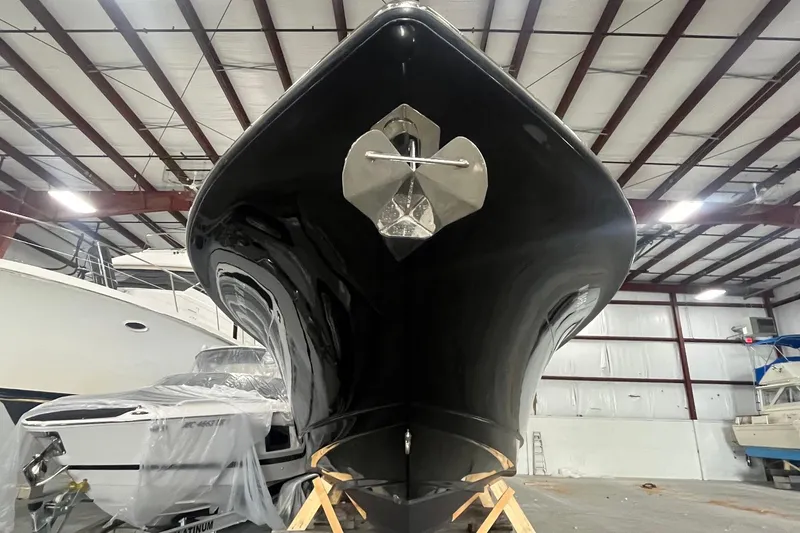 Slide: The Image of 2017 Scout 320 LXF boat in storage, showcasing sleek black hull and anchor. - 6