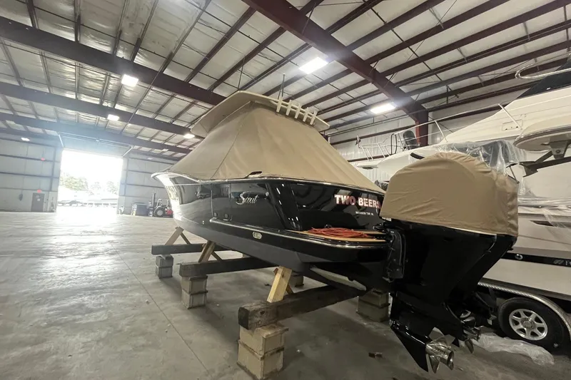 Slide: The Image of 2017 Scout 320 LXF boat covered in storage, inside a spacious warehouse. - 7