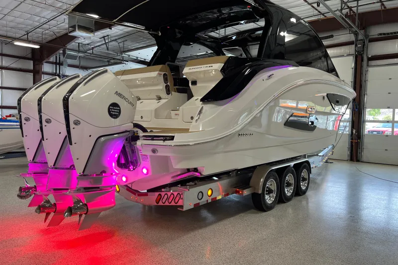 Slide: The Image of 2025 Sea Ray Sundancer 370 Outboard in showroom, featuring triple Mercury engines and vibrant lighting. - 35